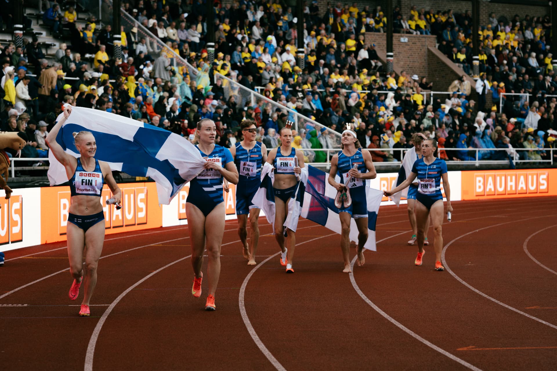 Suomen viestijoukkue juhlii Suomen lipun kanssa radalla
